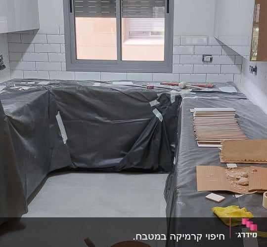 מטבח בשיפוץ עם דליים, כיסוי ניילון ואריחים
